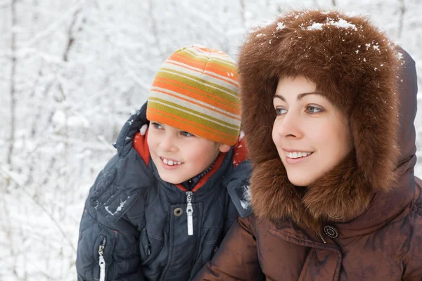 Sonriente bonita mujer y alegre chico en invierno en madera — Foto de Stock