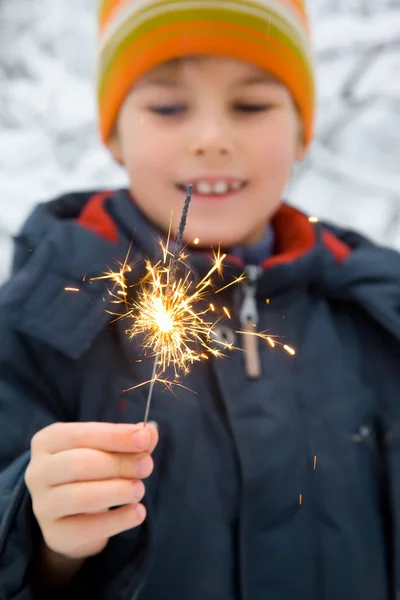 Menino alegre com fogo de Bengala na mão no inverno em madeira, Foco o — Fotografia de Stock