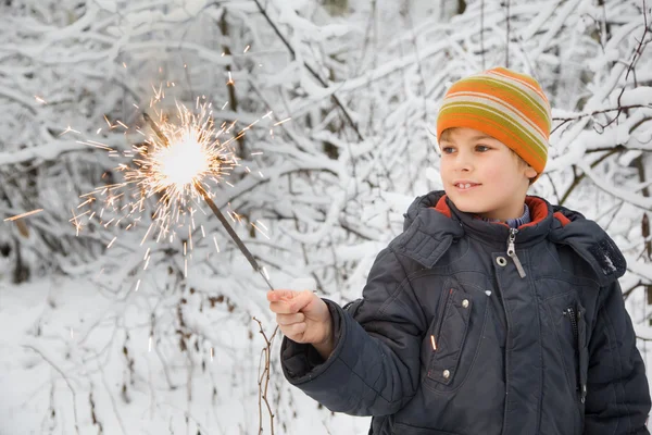 Niño alegre con fuego de Bengala en la mano en invierno en madera — Foto de Stock