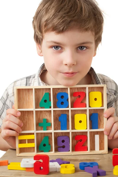 Boy in checkered shirt plays in wooden figures in form of numera — Stock Photo, Image