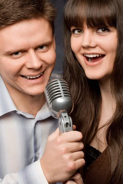 Young beautiful woman and smiling man sing in microphone — Stock Photo, Image
