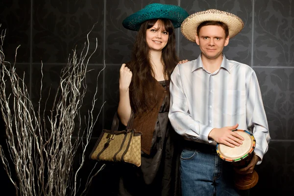 Young beautiful woman and smiling man in sombrero and with drum — Stock Photo, Image
