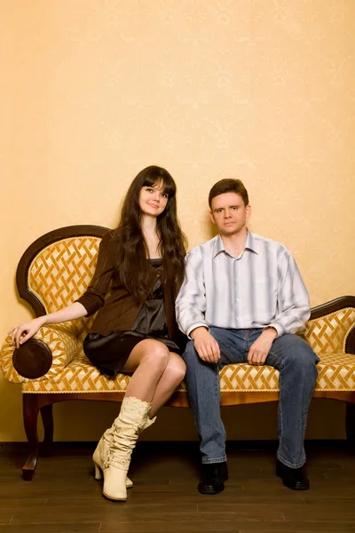 Mladá krásná žena a mladý muž sedí na pohovce v místnosti — Stock fotografie