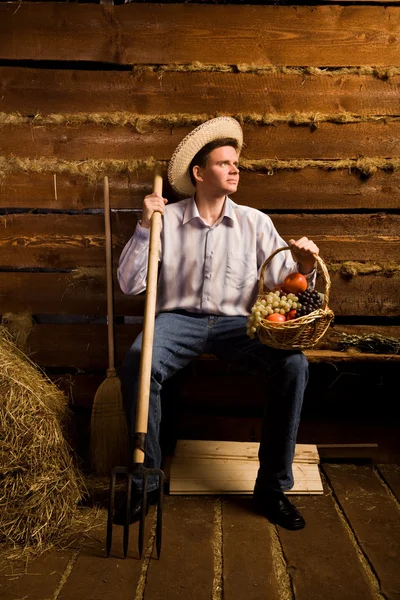 Jongeman met pitchfork, met mandje van fruit en in stro hoed — Stockfoto