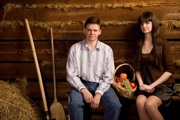 Joven hombre y mujer cerca de la cesta de fruta sentado en el banco — Foto de Stock