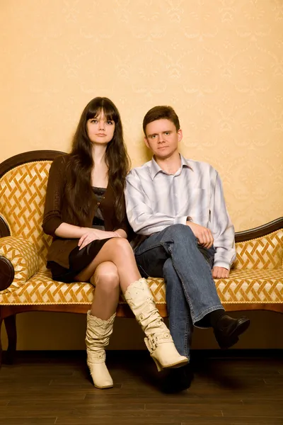 Giovane donna e giovane uomo seduto sul divano in camera — Foto Stock