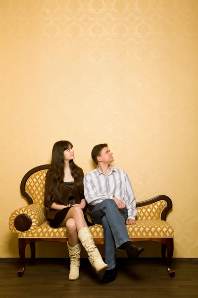 Giovane bella donna e giovane uomo seduto sul divano in camera — Foto Stock