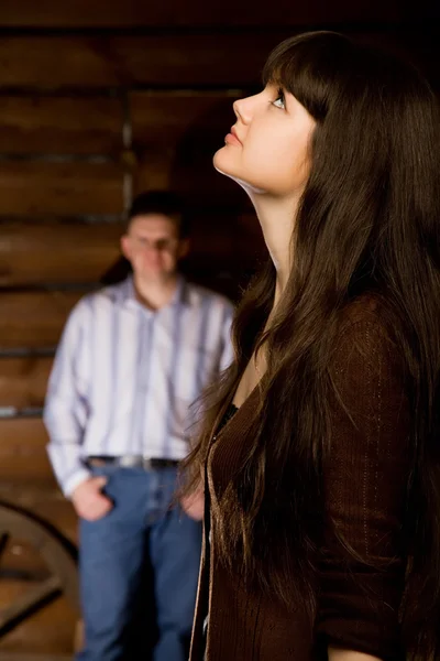 Beautiful woman brunette and young man in wooden log hut — Stock Photo, Image