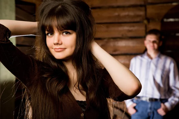 Beautiful young woman brunette and young man in wooden log hut — Stock Photo, Image