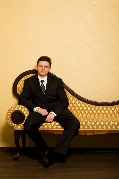 Uomo d'affari in giacca e cravatta seduto sul divano in camera — Foto Stock