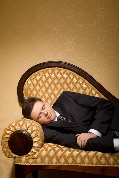Businessman in suit sleeping on sofa in room — Stock Photo, Image