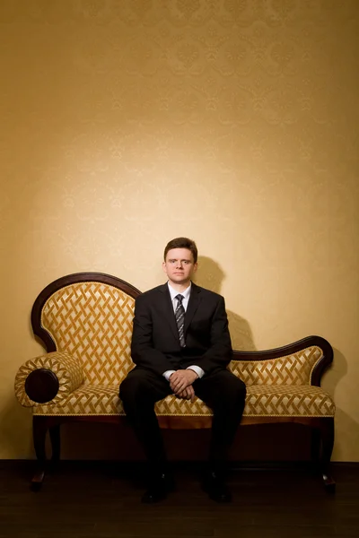 Empresario de traje sentado en el sofá en la habitación —  Fotos de Stock