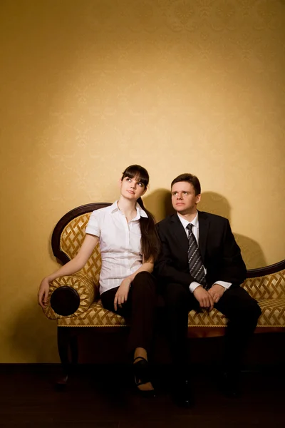Young beautiful woman and businessman in suit sitting on sofa — Stok fotoğraf