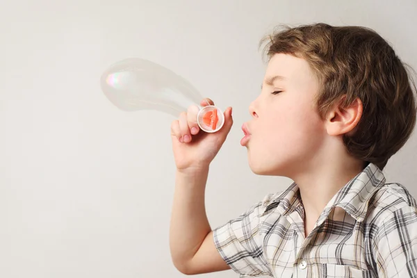Pequeño chico caucásico soplando burbujas de jabón sobre fondo blanco, s — Foto de Stock