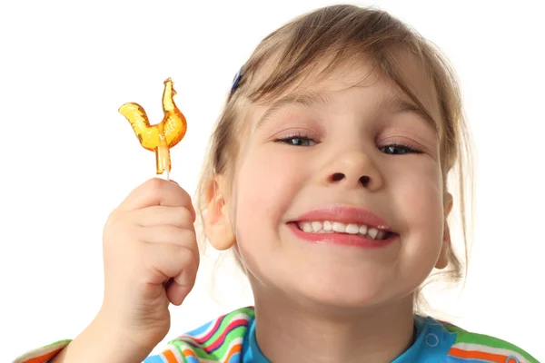 Liten flicka anläggning orange lollipop, leende och tittar på kom — Stockfoto