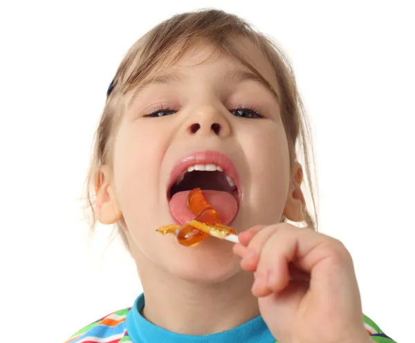 Klein meisje oranje lollipop likken en kijken naar camera, isola — Stockfoto