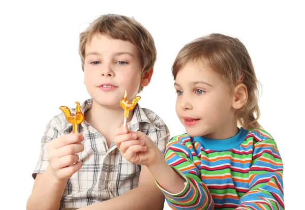 Little boy and girl holding lollipops and looking on it, half bo — Stock Photo, Image