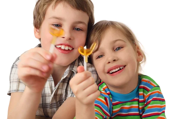 Ragazzino e ragazza in possesso di lecca-lecca, guardando su di esso e ridere — Foto Stock