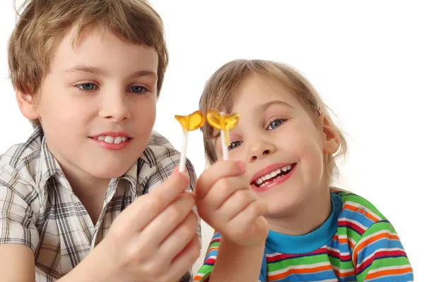 Kisfiú és a lány holding nyalókák, a ez látszó, és mosolyogva — Stock Fotó