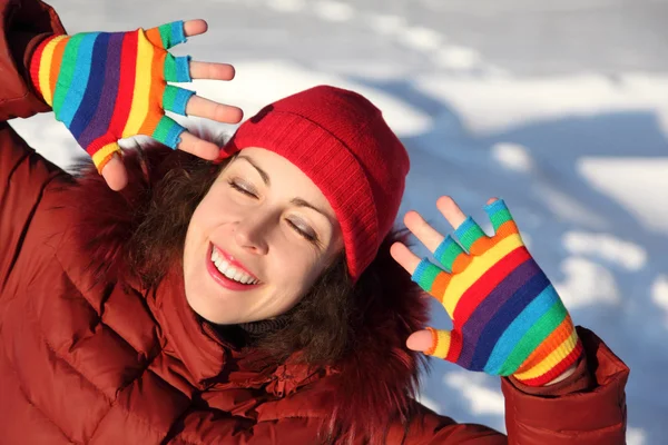 Young beauty girl in multicolored mittens smiling and putting ha — Stock Photo, Image
