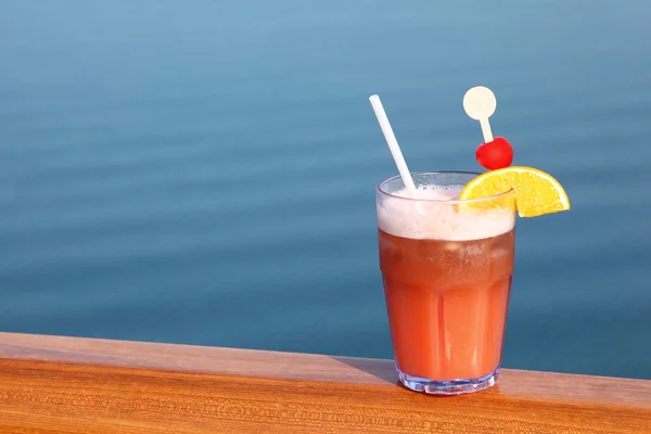 Cóctel con frutas en vidrio en el carril de cubierta del barco, mar en el backgrou — Foto de Stock