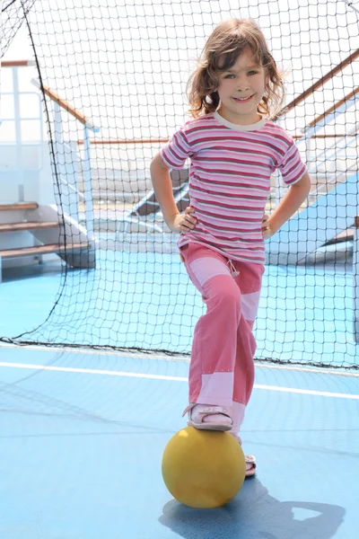 Little girl with yellow ball standing near football goal on crui — Stock Photo, Image