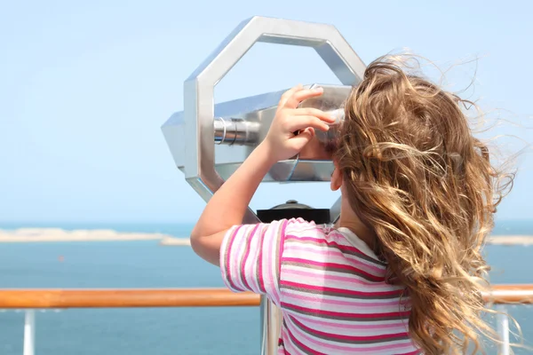 Bambina in piedi sul ponte della nave da crociera e guardando in binocolo — Foto Stock