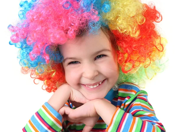 Klein meisje in clown pruik glimlachen en kijken naar camera, kin op — Stockfoto