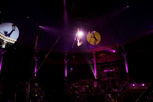 Desempenho do circo com duas ginastas trapézio luz roxa — Fotografia de Stock