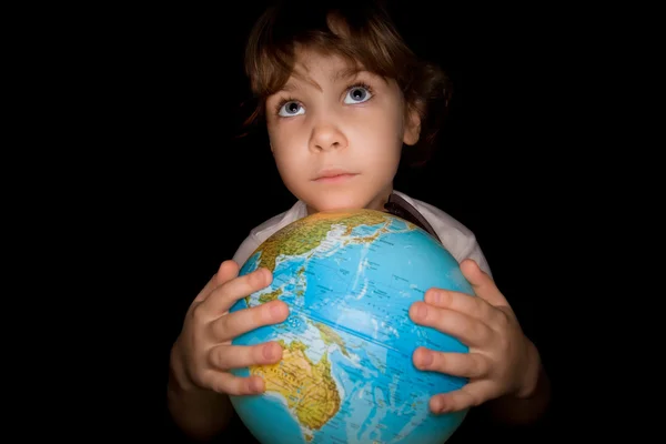 Little girl keeps in hands over globe of world isolated on black — Stock Photo, Image