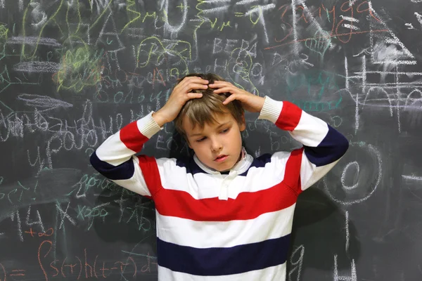 Pupil standing near school board and hold on his head half body — Stock Photo, Image