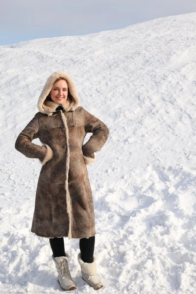 Young beauty woman in long coat standing on snowy area and smili — Stock Photo, Image