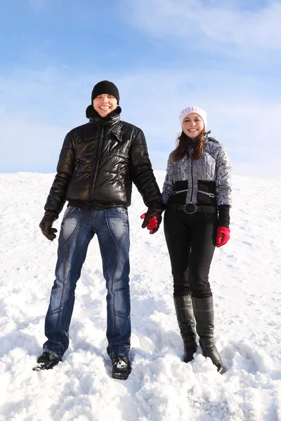 Young man and girl standing on snowy area, holding for hands and — Stock Photo, Image
