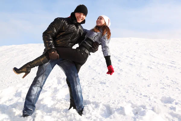 Young man and girl dance on snowy area and smiling, man looking — Stock Photo, Image