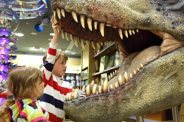 Ragazzino e ragazza in cerca di tirannosauro aperto bocca fuoco — Foto Stock