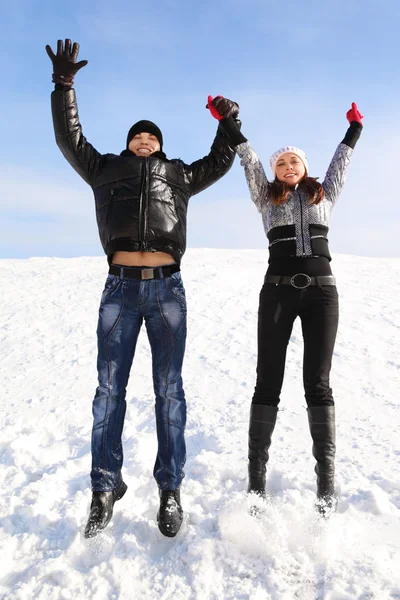 Young man and girl jump on snowy area and smiling, holding for h — Stock Photo, Image