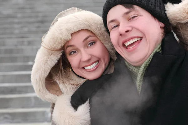 Young girl in coat with hood embracing man from back and laughin — Stock Photo, Image