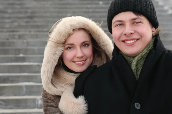 Chica joven en abrigo con capucha abrazando al hombre de la espalda y sonriendo —  Fotos de Stock