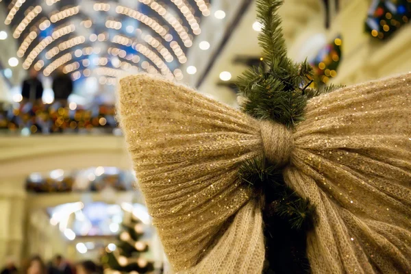 Christmas ornament in form of bow on fur-tree in shopping centre — Stock Photo, Image