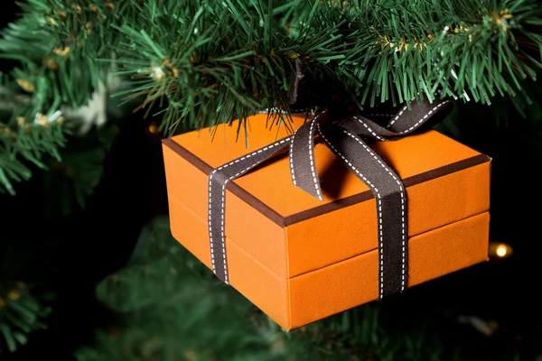Presente comemorativo em caixas amarelas penduradas no Natal artificial — Fotografia de Stock