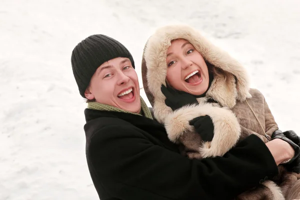 Joven hombre y chica en vestido cálido riendo, abrazando y mirando — Foto de Stock