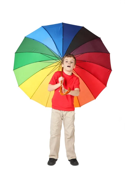 Маленький мальчик в красной рубашке открыл рот с большим разноцветным зонтиком — стоковое фото