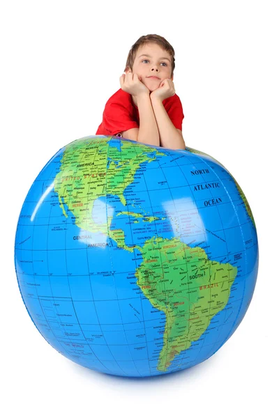 Garçon en chemise rouge se penche sur globe gonflable menton sur les mains isolat — Photo