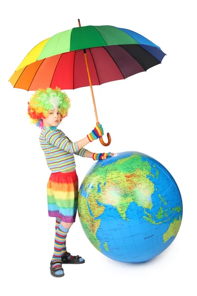Chlapec v šatech klaun s deštníkem a velký glóbus izolovaných na bílém — Stock fotografie