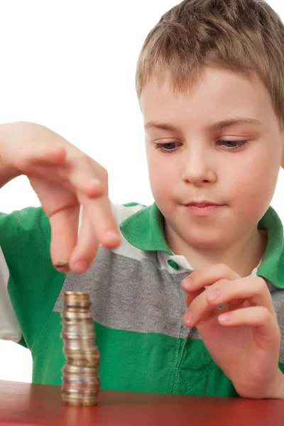 Junge im gestreiften T-Shirt stapelt Münzen isoliert auf weißem Bac — Stockfoto