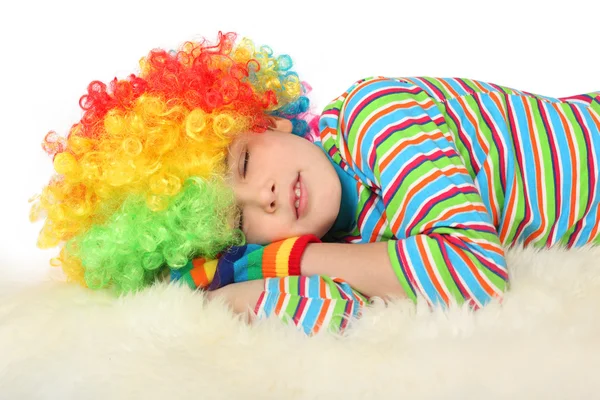 Мальчик в клоунском платье спит на белом фоне — стоковое фото