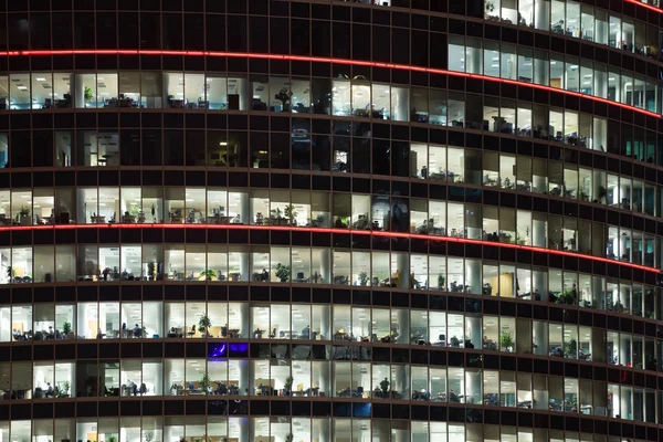 Moderne Bürogebäude mit großen Fenstern in der Nacht, in Fenstern — Stockfoto