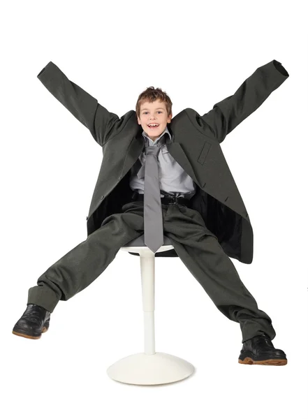 Menino no terno grande homem cinzento sentado na cadeira e sorrindo i — Fotografia de Stock