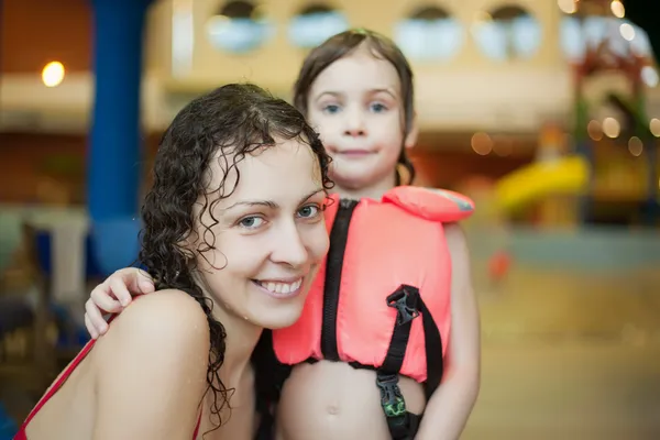 Smiling beautiful woman and little girl in lifejacket after swi — Stock Photo, Image