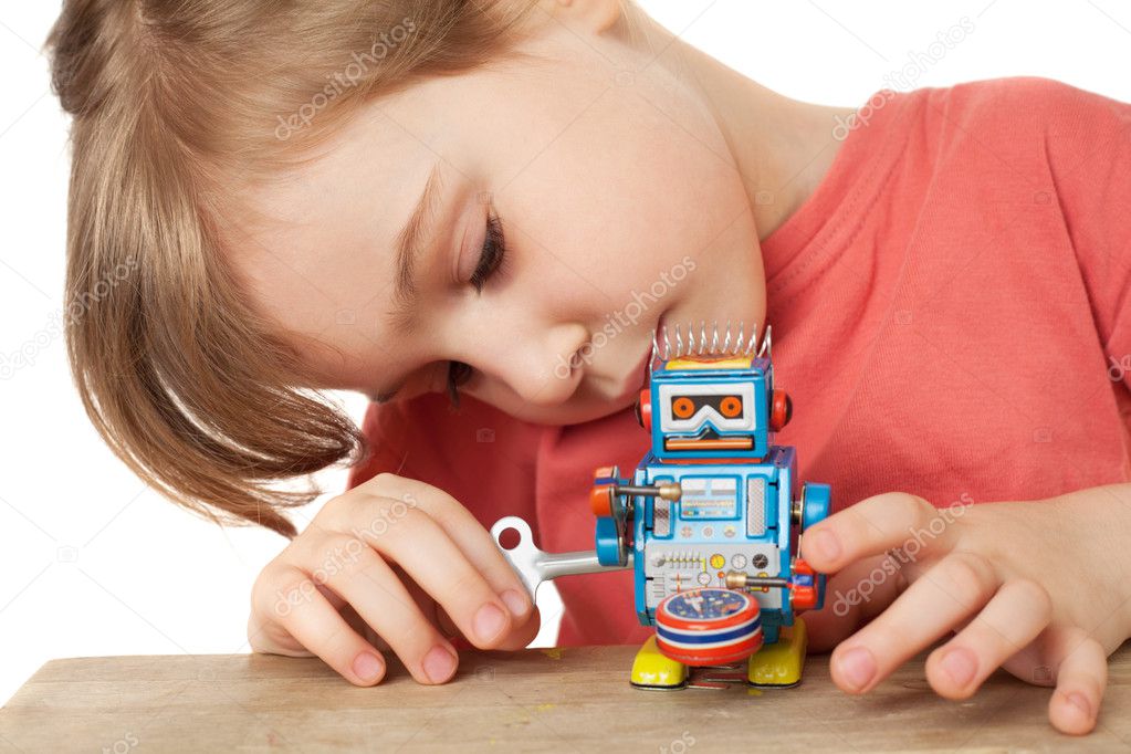 Little girl in red T-shirt plays with clockwork robot isolated o